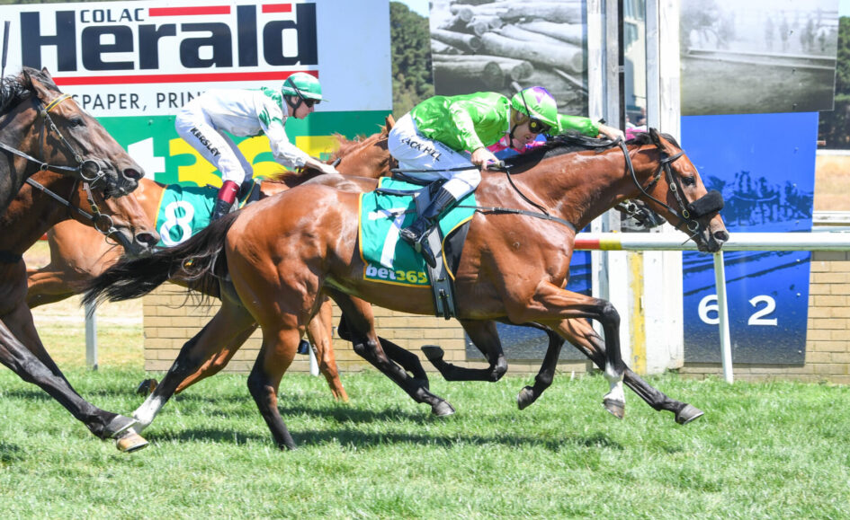 Jockeys on racing horses sprint toward the finish line, green and white silks, number 7 visible on the lead horse, on a grassy track.