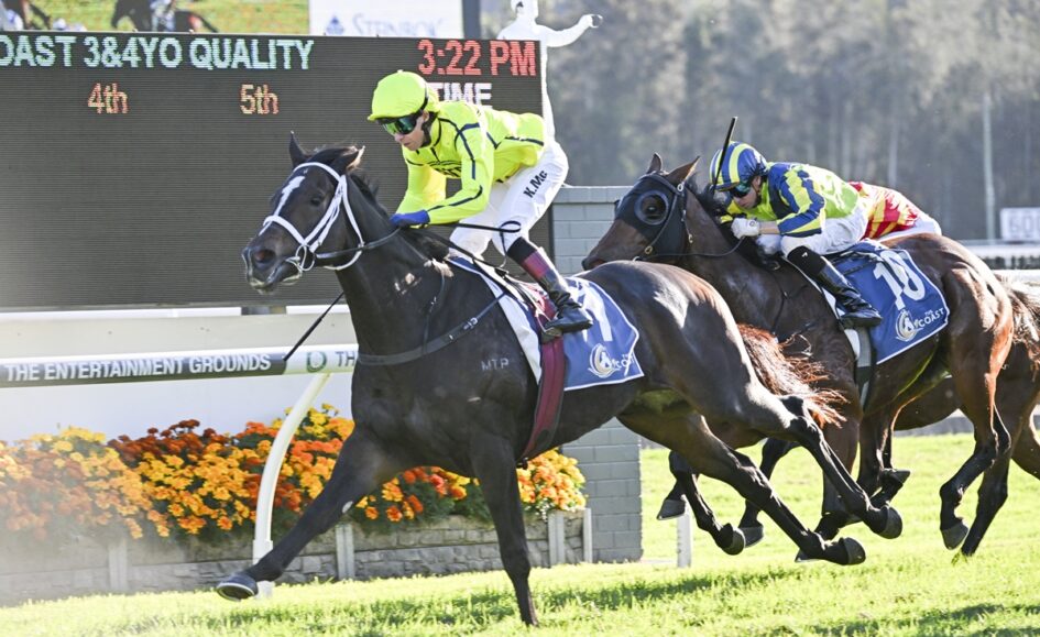 Leading dark bay horse and jockey in neon yellow silks sprint toward the finish, flanked by two rival horses and riders on a turf track.