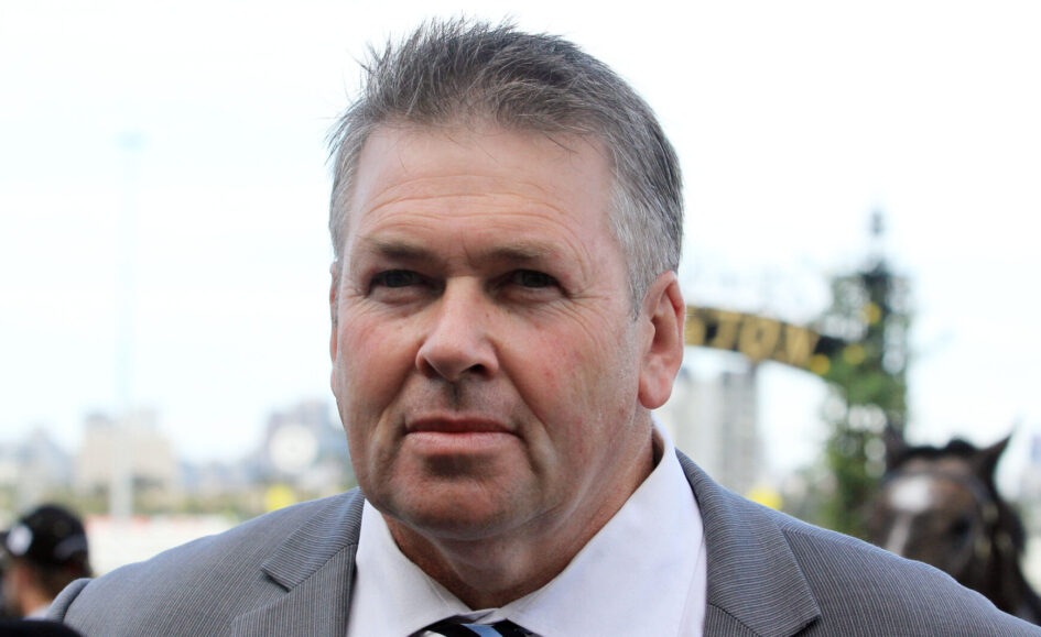 Man in a gray suit and striped tie at an outdoor event, facing the camera with a slight smile.