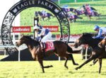 Jockey on horse #10 leads a race at Eagle Farm under a decorative arch with spectators in the background.
