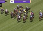 Group of thoroughbred horses racing on a green turf track with jockeys in colorful silks; on-screen graphics show 'R3' and '1005m'