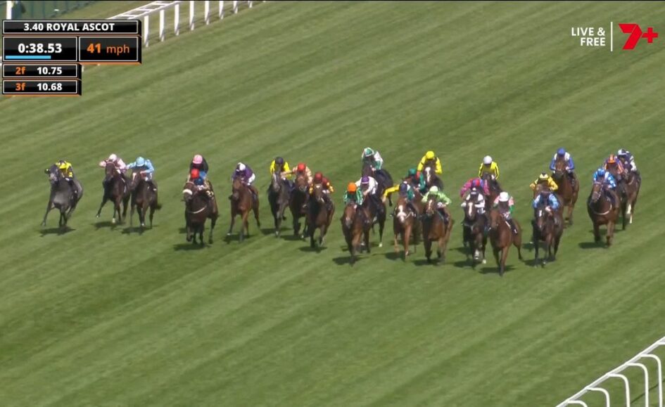 Crowded horse race on a green turf track with colorful jockey silks; time and speed readouts appear at the top-left (Royal Ascot).