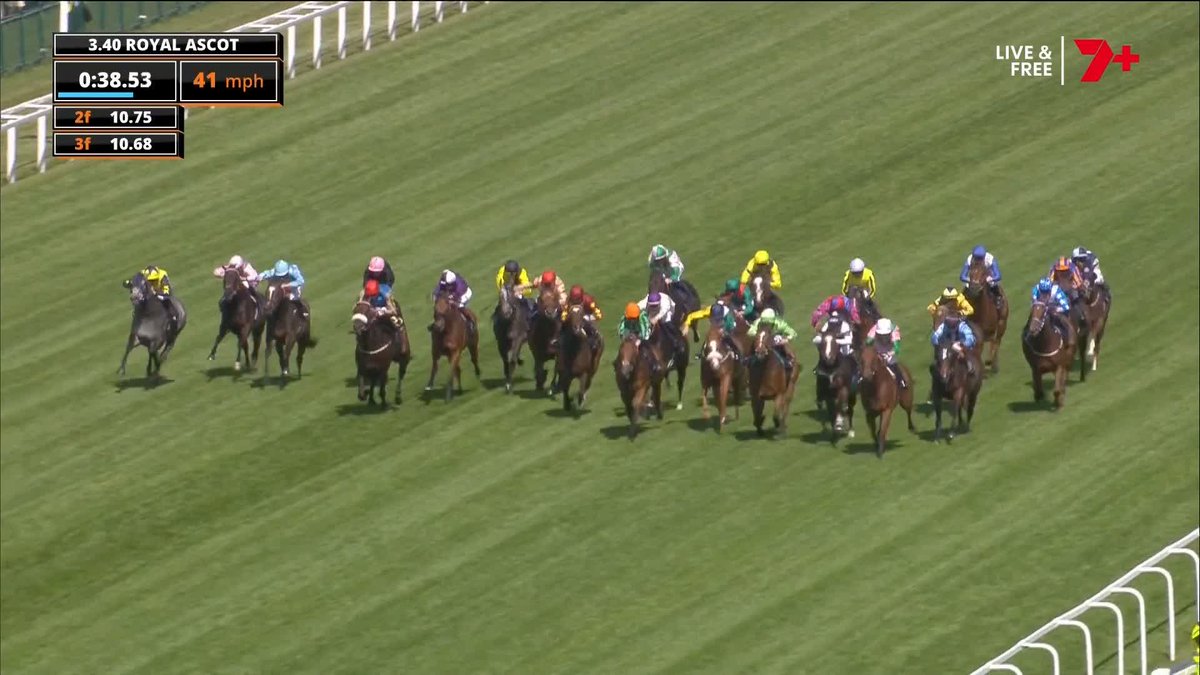 Crowded horse race on a green turf track with colorful jockey silks; time and speed readouts appear at the top-left (Royal Ascot).