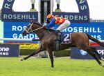 Jockey in red-yellow checkered silks riding a brown horse, number 2, galloping on a grass track at Rosehill Gardens with a blue sign in the background.
