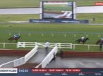 Horse race on a turf track with a large screen and race banners in the background